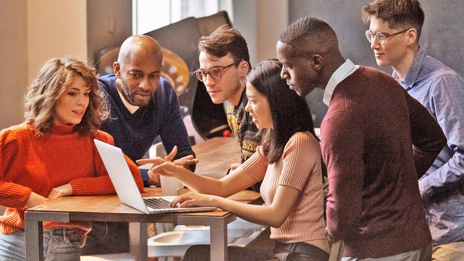 A group of people gathered around a laptop.