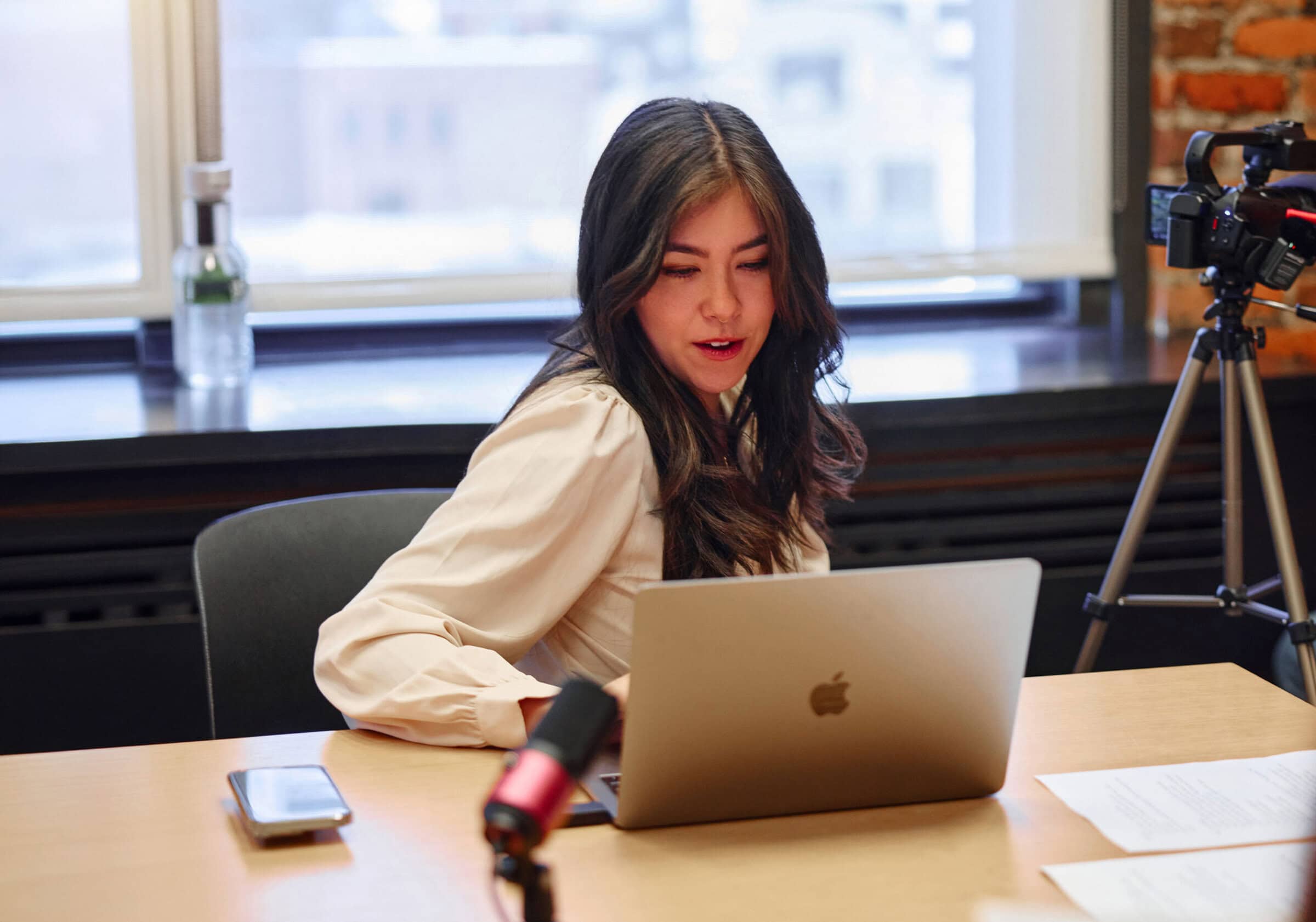 Woman on laptop with a red microphone behind it