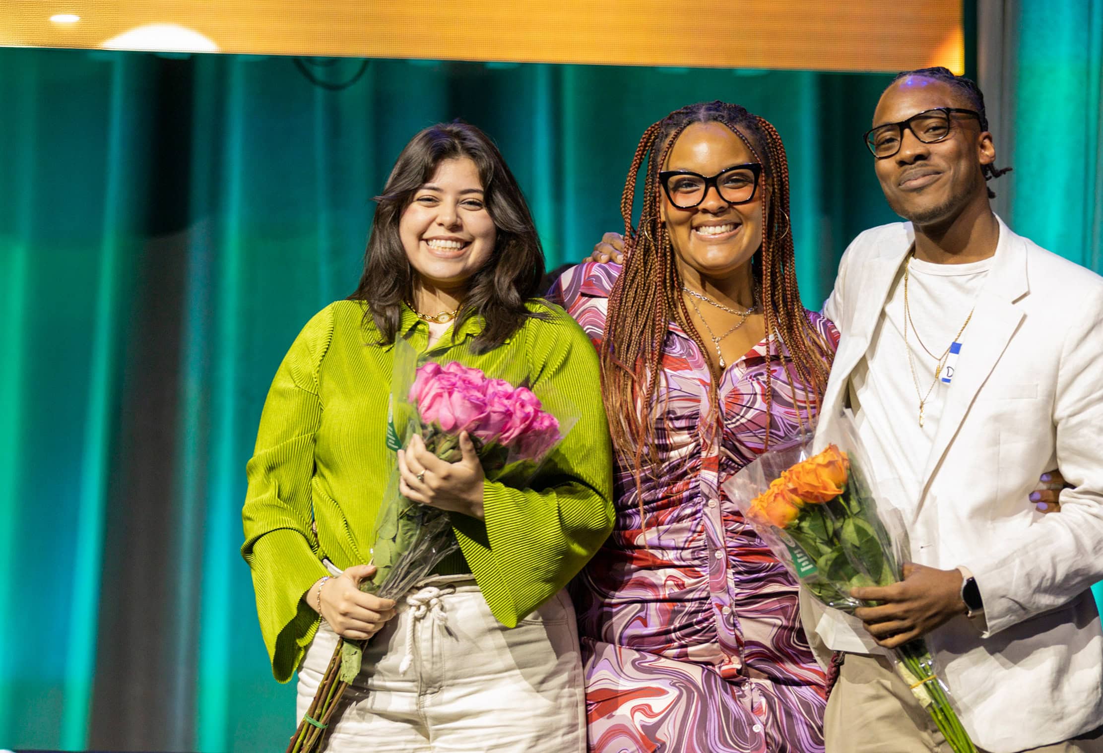 Group of people holding flowers and smiling at camera