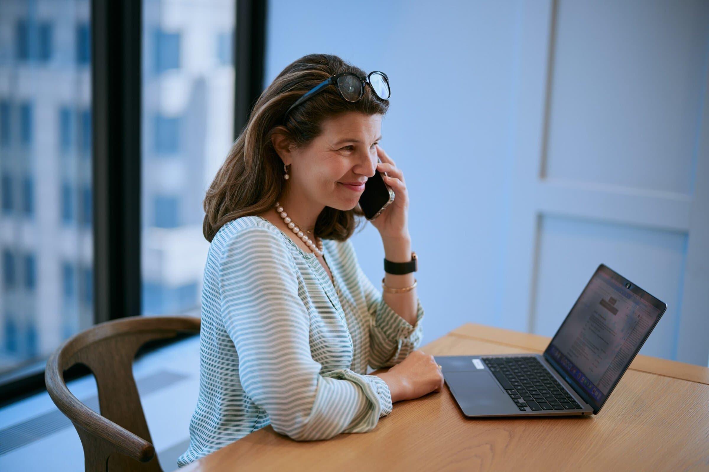 person on the phone, smiling with a laptop near them