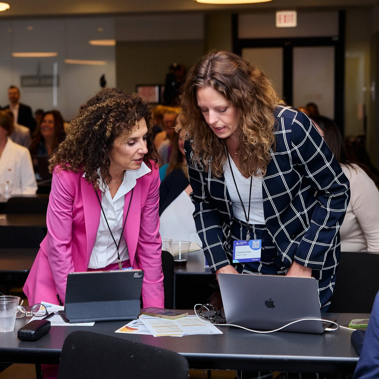 Two women looking at their laptops and chatting
